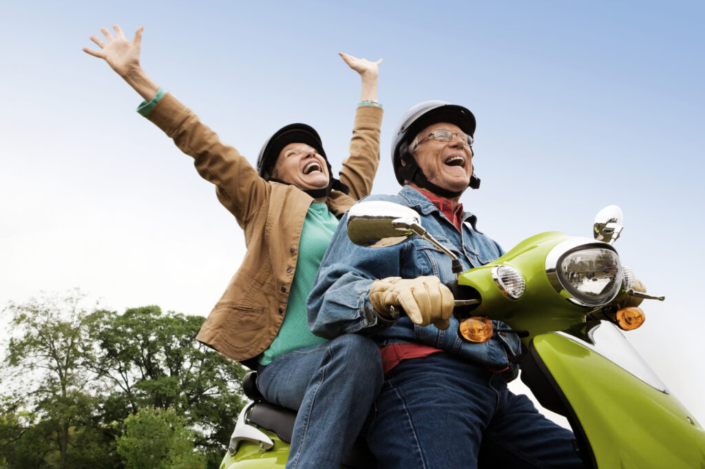 Elderly couple expressing joy on scooter. www.durhamexecutivegroup.com