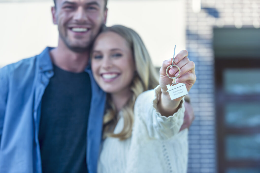 Young couple holding keys to success regarding how to sell your Troy Burne Golf Village home 